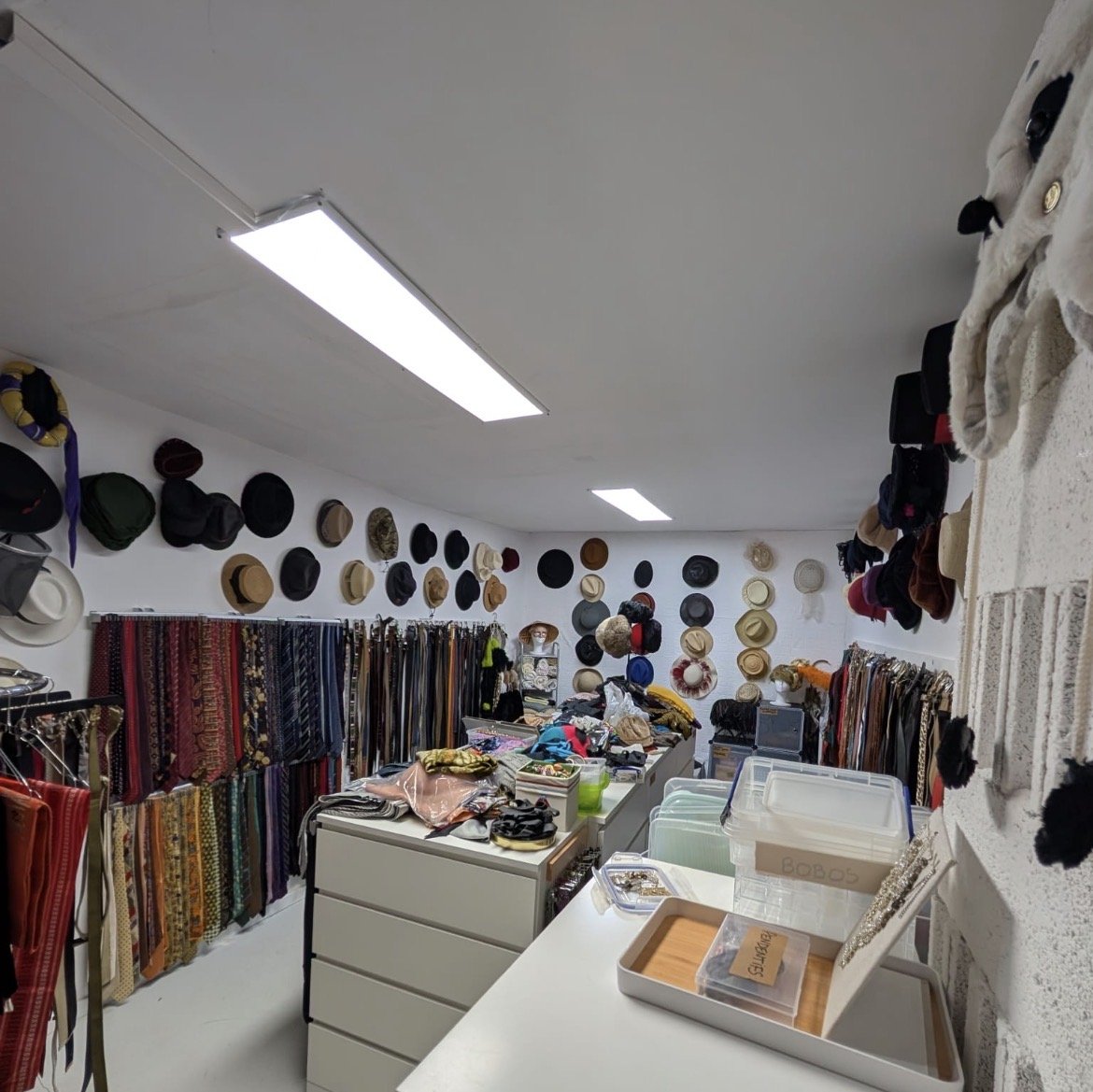 Salle accessoires Sud Costumes — chapeaux, cravates et bijouterie organisés par catégorie