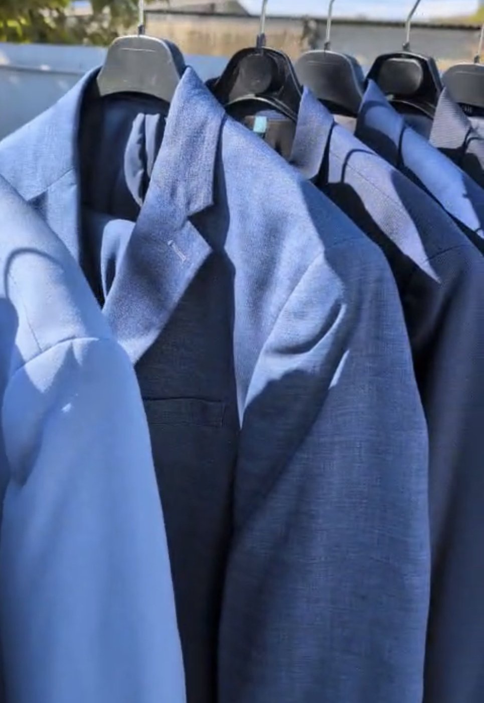 Vestes de costume hommes dans les tons bleus alignées sur portant
