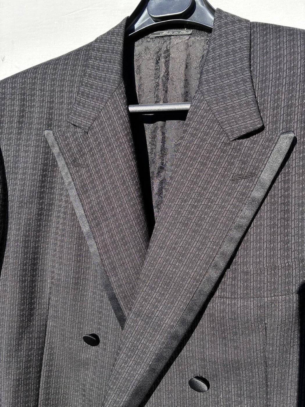Détail d'une veste de smoking gris à rayures, revers cranté satin