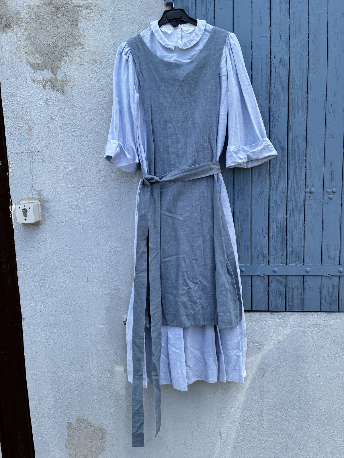 Habit de religieuse posé à plat : robe gris clair à plis, scapulaire droit gris foncé et ceinture assortie (voile en coton gris foncé non visible sur cette vue)