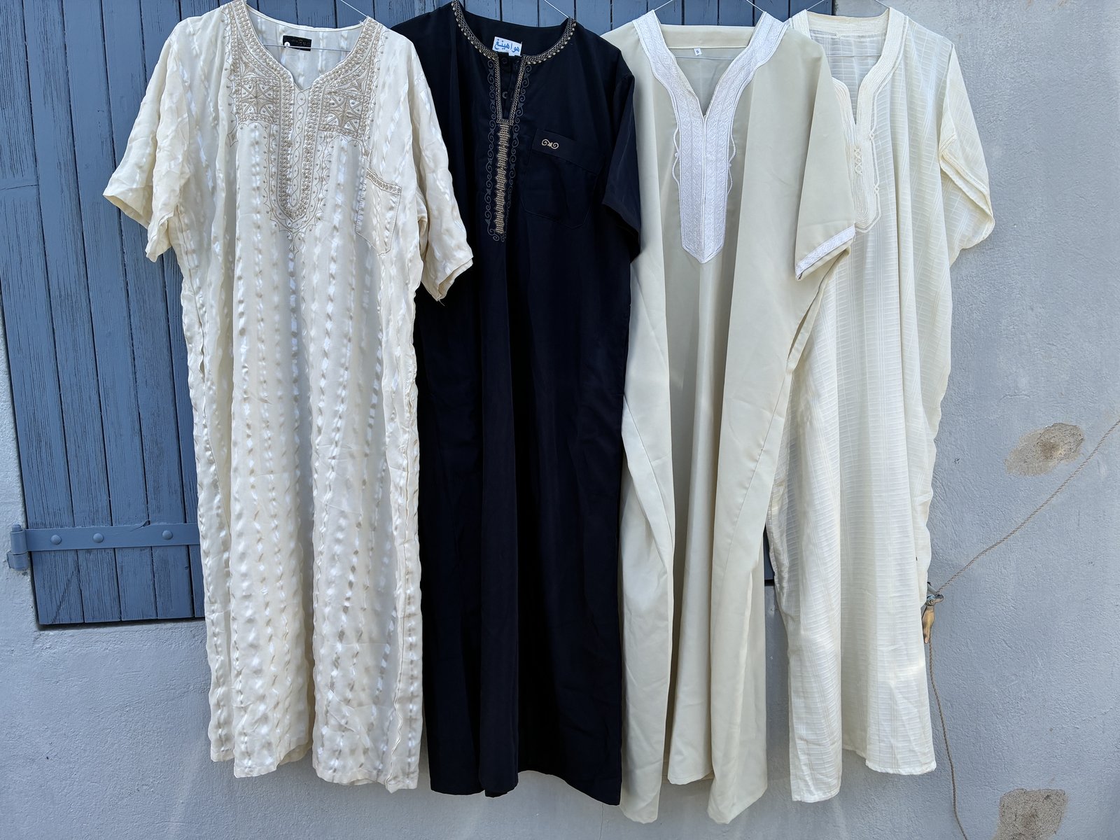 Quatre tuniques traditionnelles : blanche brodée, noire à col brodé, écrue col V, écrue rayée