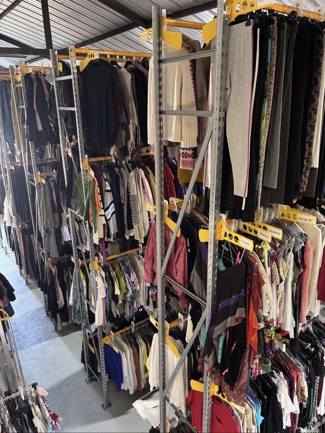 Vue plongeante sur les rayonnages denses du showroom Sud Costumes