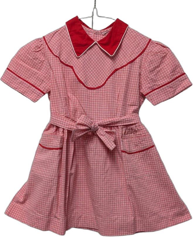 Robe écolière années 50-60 : vichy rouge et blanc, col Claudine rouge bordé blanc, manches courtes ballon, ceinture nouée à la taille, 2 poches plaquées à passepoil rouge